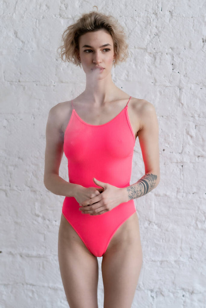 young beautiful woman pose in pink bodysuit in studio - 写真・画像