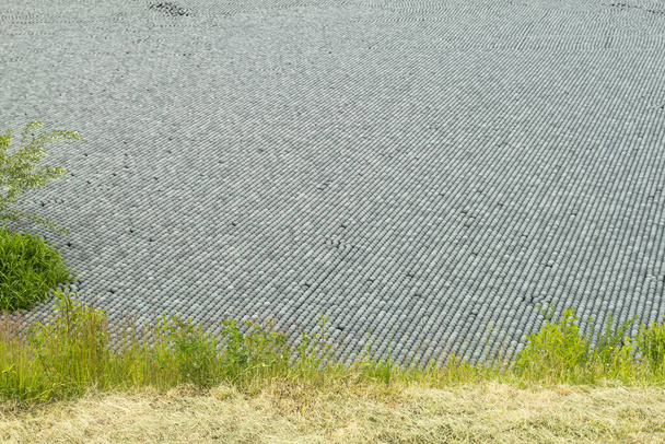 Zwarte plastic ballen voor het vullen van reservoirs. Schaduwbolletjes zijn kleine plastic bolletjes die op het oppervlak van de tank drijven en voorkomen dat water verdampt. - Foto, afbeelding