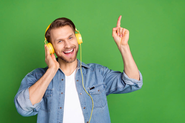 Photo portrait of young guy listening music wearing headphones dancing enjoying isolated vibrant green color background - Φωτογραφία, εικόνα