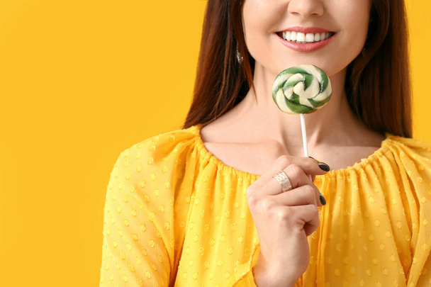 Beautiful young woman with sweet lollipop on color background - Fotó, kép