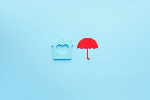 Figura de la casa con paraguas sobre fondo de color. Concepto de seguro inmobiliario - Foto, imagen