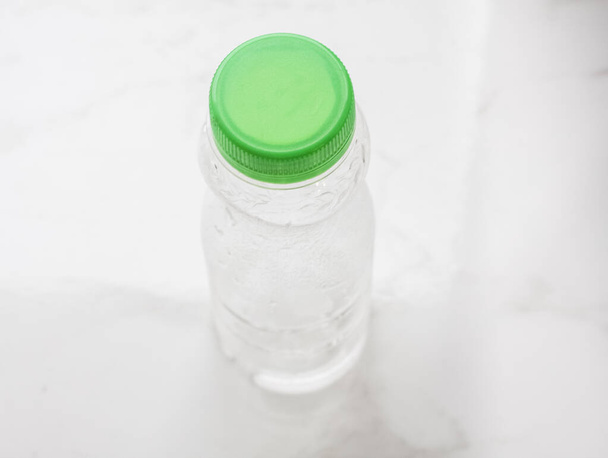 Kunststof flessen op een lichte ondergrond met en zonder water - Foto, afbeelding