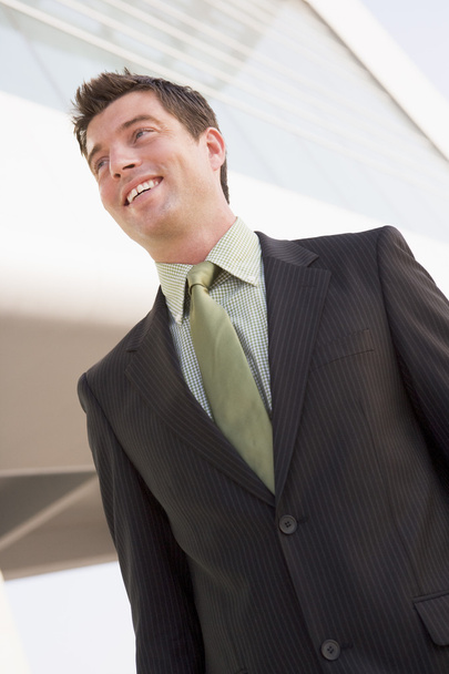 Businessman standing outdoors by building smiling - Photo, image