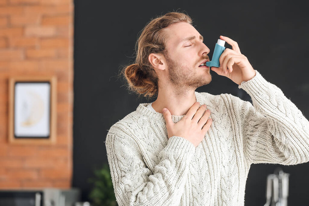 Young man with inhaler having asthma attack at home - 写真・画像