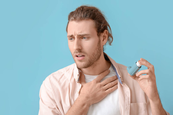Młody człowiek z inhalatorem z atakiem astmy na tle koloru - Zdjęcie, obraz