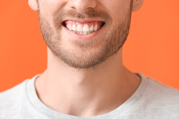 Lächelnder junger Mann auf farbigem Hintergrund, Nahaufnahme - Foto, Bild