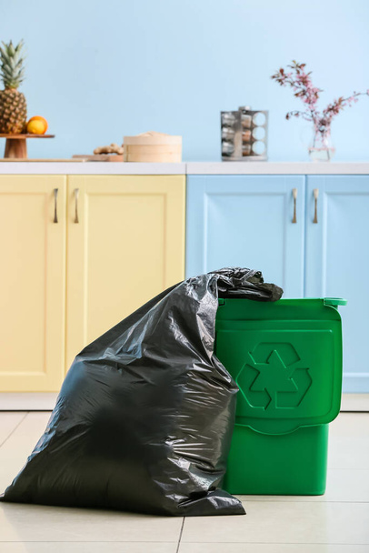 Bag with garbage and rubbish bin with logo of recycling at home - Photo, image