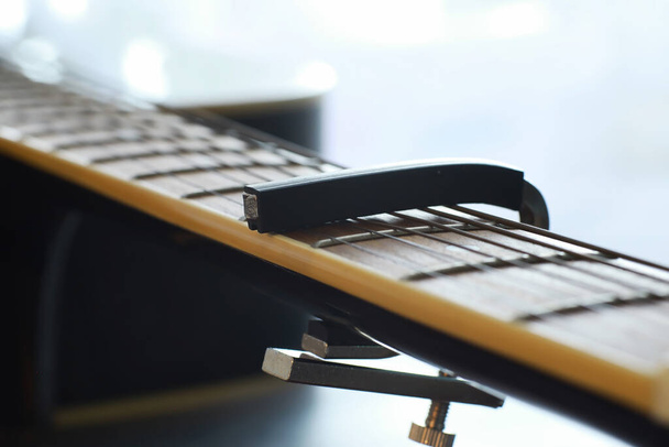Ακουστική κιθάρα για καλλιτέχνη που παίζει έγχορδο μουσικό όργανο στη σκηνή. Μαύρη κιθάρα με κάπο. Μουσικό υπόβαθρο. - Φωτογραφία, εικόνα