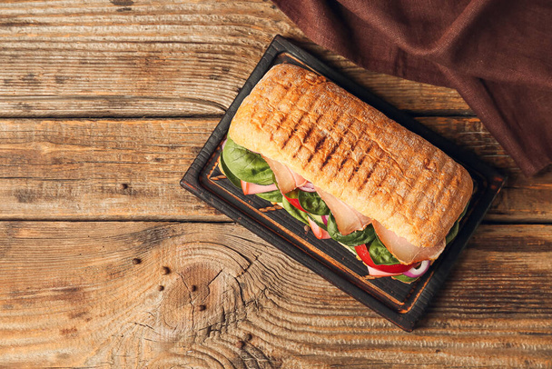 Дошка зі смачним бутербродом чіабата на дерев'яному фоні
 - Фото, зображення