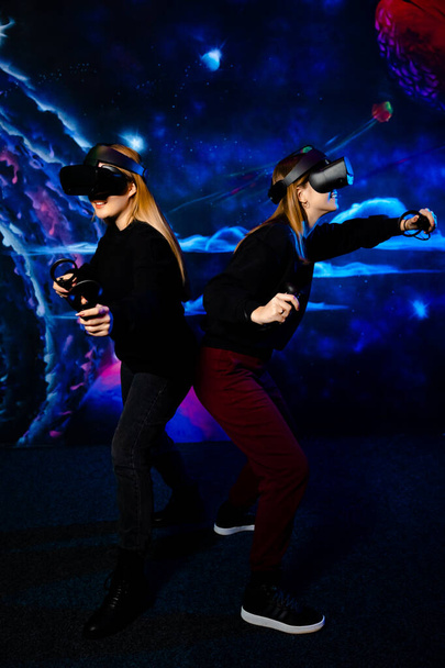 Twee jonge meisjes zussen vriend met virtuele bril veel plezier samen en videospelletjes spelen.  - Foto, afbeelding