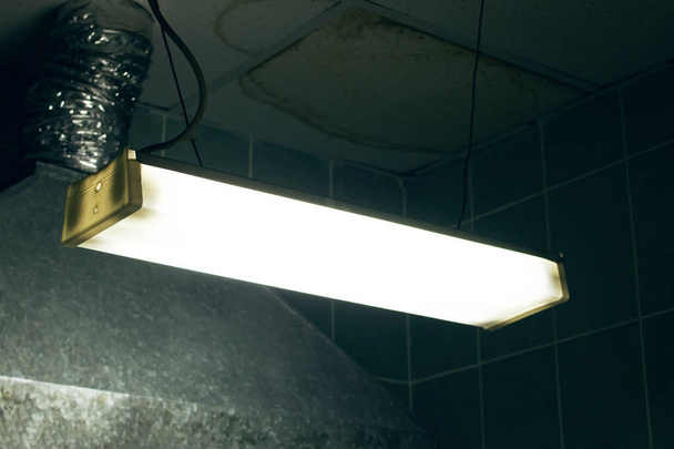 Lâmpada fluorescente velha em um quarto escuro assustador de perto - Foto, Imagem