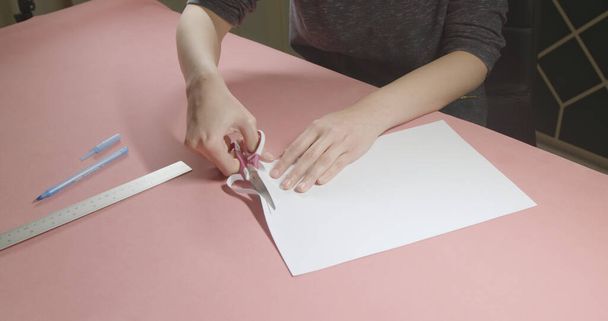 girl cuts paper with scissors - Foto, afbeelding