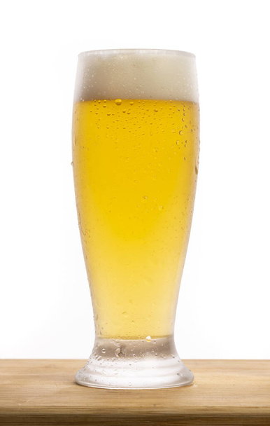 Ποτήρι μπύρας σε ξύλινο τραπέζι πάνω σε λευκό φόντο. - Φωτογραφία, εικόνα