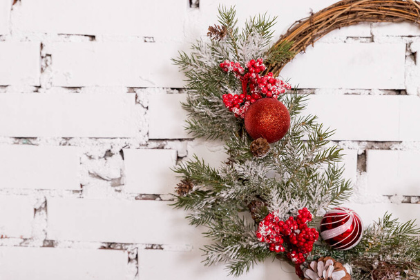 Een traditionele heldere kerstkrans hangend boven de open haard, op een witte bakstenen muur.Kerstconcept, nieuwjaar decor.kamer in Loft stijl.Kopieer ruimte - Foto, afbeelding