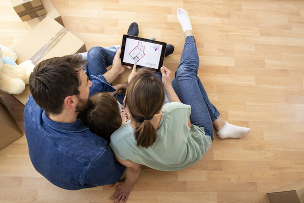 House moving concept - top view of happy family choosing house interior design on tablet computer. - Fotó, kép