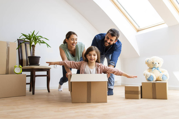 Home, people, moving and real estate concept - happy family with children enjoying very first day in new house and riding in cardboard boxes. - Zdjęcie, obraz