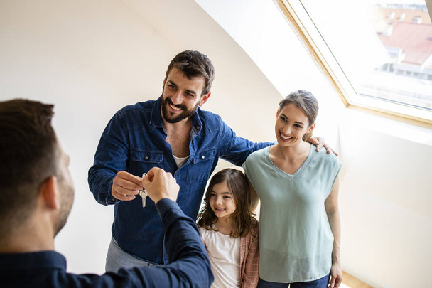 Happy family with children buying property or receiving keys of new home from real estate agent. Moving into new apartment. - Fotoğraf, Görsel