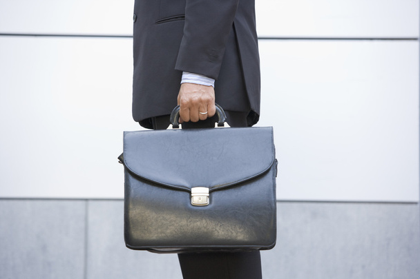 Businessman holding briefcase outdoors - 写真・画像