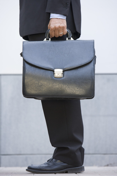 Businessman holding briefcase outdoors - Foto, afbeelding