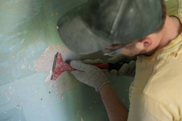 Hombre caucásico quitando pintura vieja con herramienta de raspador. - Foto, Imagen