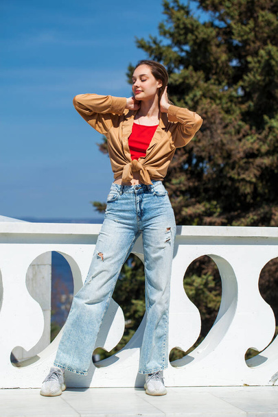 Full length portrait of a young stylish girl in a beige blouse with long sleeves and blue jeans - Photo, image