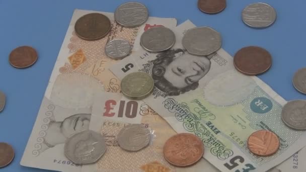 Sterling UK espèces et pièces de monnaie tournant sur un fond bleu
. - Séquence, vidéo