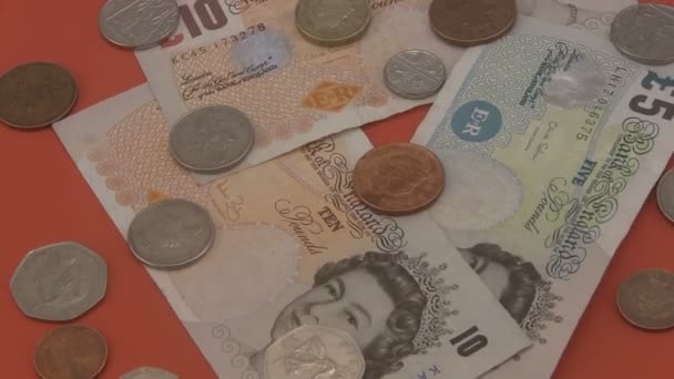 στερλίνα Ηνωμένο Βασίλειο μετρητά και κέρματα περιστρεφόμενο κόκκινο φόντο. - Πλάνα, βίντεο
