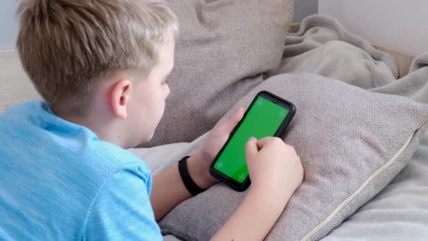 Menino 4K segurando seu smartphone com tela verde, rolando tela sensível ao toque - Filmagem, Vídeo