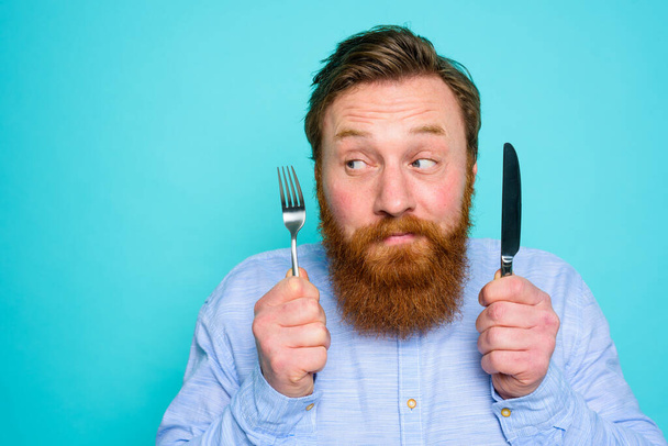 Man with tattoos is ready to eat with cutlery in hand - Photo, Image