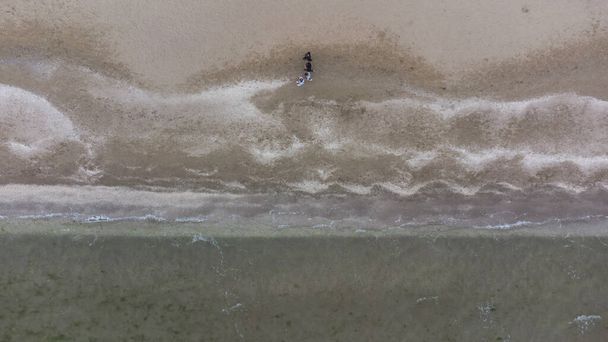 Luftaufnahme von Sandstrand und Meer an einem bewölkten Frühlingstag. Menschen laufen am Strand entlang - Foto, Bild
