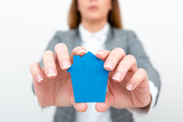 A Lady Holding Home In Business Outfit Presenting Possibility Of Owning Your Own Real Estate. Buying House Or Moving New Insurance Or Mortage Concept Shown By The Young Businesswoman. - Foto, afbeelding