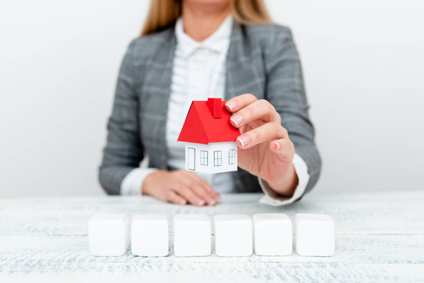 A Lady Holding Home In Business Outfit Presenting Possibility Of Owning Your Own Real Estate. Buying House Or Moving New Insurance Or Mortage Concept Shown By The Young Businesswoman. - Foto, immagini