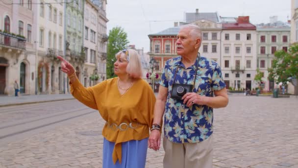 Старшие старые стильные туристы мужчина, женщина, бабушка, дед семьи, имеющие прогулку в летнем городе - Кадры, видео