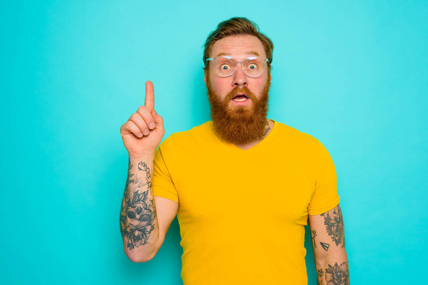 Man with yellow t-shirt and beard is shocked about something - Photo, Image