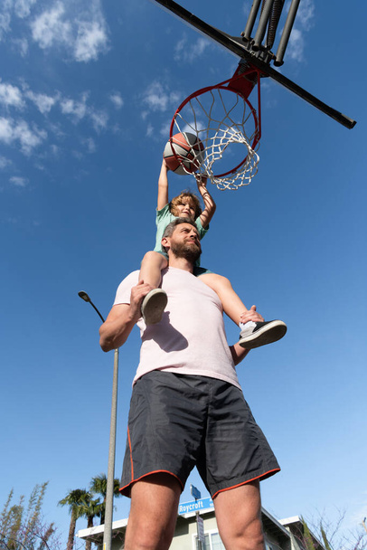 Отец и сын играют в баскетбол на открытом воздухе. Счастливого дня отца. счастливая семья - Фото, изображение