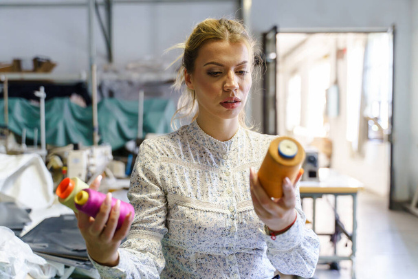 Vooraanzicht op vrouwelijke werknemer of ontwerper ondernemer kiezen draad kleur bij de fabriek creativiteit vrouwelijke ondernemers en empowerment concept - Foto, afbeelding