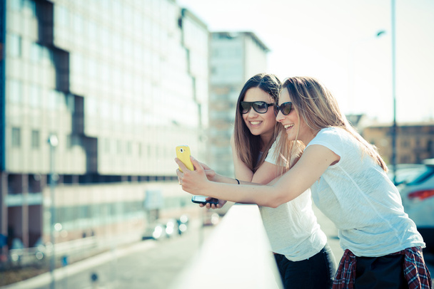 δύο όμορφες νεαρές γυναίκες, χρησιμοποιώντας έξυπνο τηλέφωνο - Φωτογραφία, εικόνα