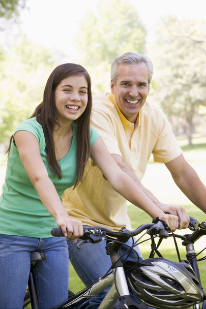 Man and girl on bikes outdoors smiling - Foto, afbeelding