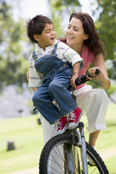 Woman and young boy on a bike outdoors smiling - Foto, imagen