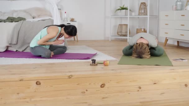 Allenatore di yoga che esercita con la giovane donna durante la classe privata a casa - Filmati, video