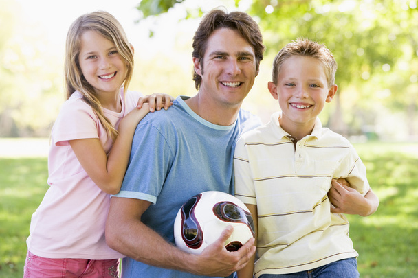 Man and two young children outdoors holding volleyball and smili - Foto, immagini