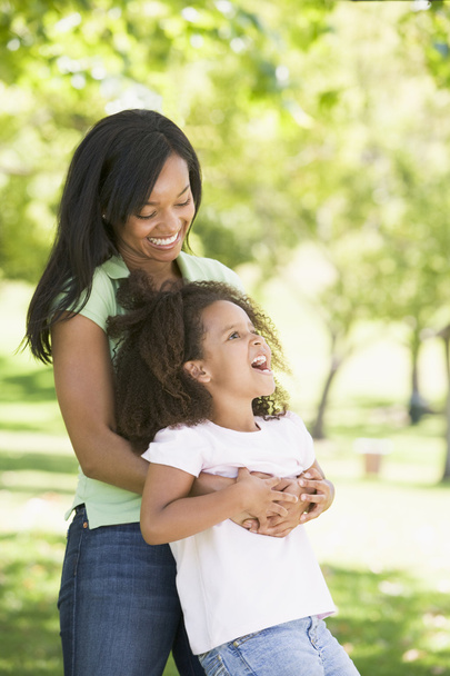 Woman and young girl outdoors embracing and smiling - Photo, image