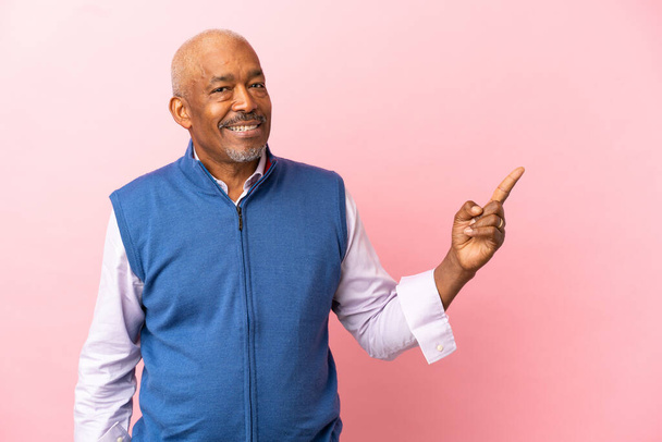 Cuban senior isolated on pink background pointing finger to the side - Photo, Image