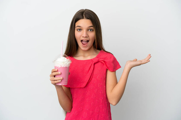 Маленька дівчинка з полуничним молочним коктейлем над ізольованим білим тлом з шокованою експресією обличчя
 - Фото, зображення