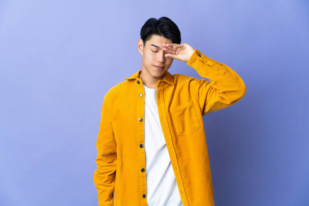 Young Chinese man isolated on purple background with tired and sick expression - Фото, изображение
