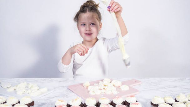 Schritt für Schritt. Kleines Mädchen übt das Einfügen von Buttercreme in ein Schneidebrett - Foto, Bild