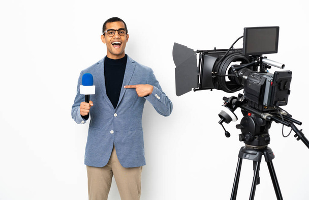 Muhabir Afrikalı Amerikalı bir adam mikrofon tutuyor ve sürpriz bir yüz ifadesiyle izole edilmiş beyaz bir arkaplanda haberleri sunuyor. - Fotoğraf, Görsel