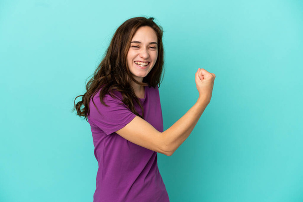 Young caucasian woman isolated on blue background celebrating a victory - Photo, image