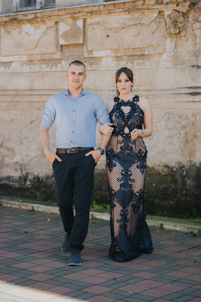 A beautiful elegantly dressed couple posing near a brick wall outdoor - Foto, afbeelding