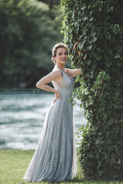 A portrait of a young woman wearing a long gray dress and posing in a park in Bosnia and Herzegovina - Photo, image